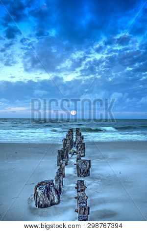 Moonset At Dawn Over A Dilapidated Pier On The Beach In Port Royal