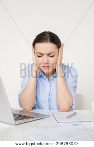 Young tense businesswoman touching her head while trying to manage with working troubles and calm down