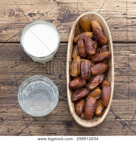 Dried Dates Fruits On A Branch, A Glasses Of Water And Milk On A Wooden Table. Traditional Fast Brea