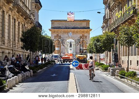 Montpellier, France - June 24, 2015: Triumphal Arch Porte Du Peyrou. Rue Foch Street. Woman Is Ridin