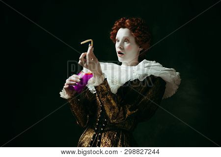 Getting Wonder. Medieval Redhead Young Woman In Golden Vintage Clothing As A Duchess Eating A Fried 
