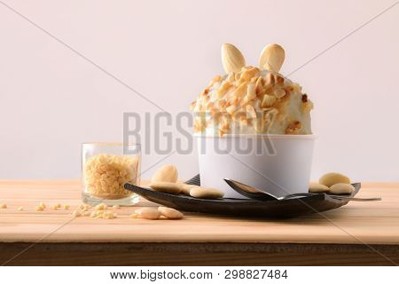 Almond Ice Cream Cup Decorated With Almond Pieces On A Plate On A Wooden Table. Horizontal Compositi