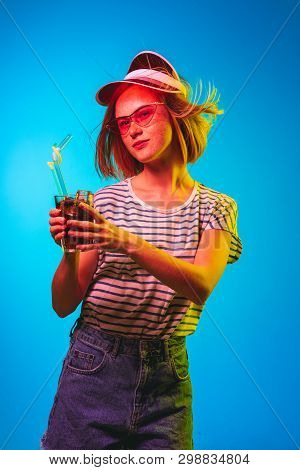 Beautiful Female Half-length Portrait Isolated On Blue Neon Lights Studio Background. Young Woman In