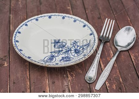 Vintage Plate With Fork And Spoon In A Wooden Table