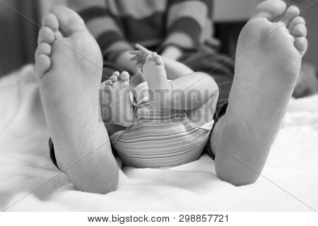 Closeup Of Huge Feet Of Father And Little Newborn Baby
