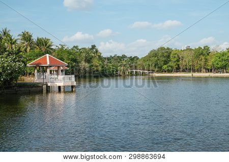 Landscape View Of A Lake And Waterfront Pavilions Surrounded By Lush Green Forest In Sri Nakhon Khua