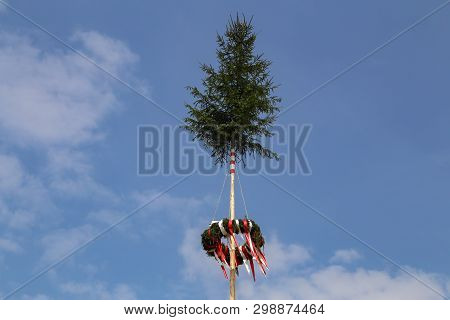 A Traditional Maypole With Colored Ribbons On Blue Background
