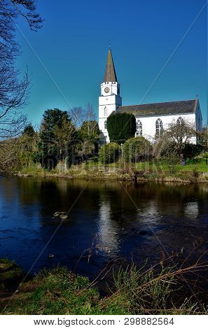 A View Of The White Church Building On The Banks Of The River Earn In Comrie, Perthshire