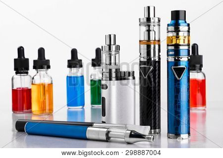 Electronic Cigarettes And Bottles With Vape Liquid On White Background