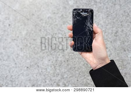 Smartphone With A Broken Screen Glass In Hand Of Young Woman. Copy Space