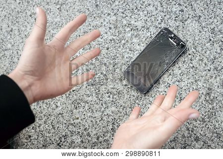 Shocked Young Woman Throws Up Her Hands, Her Phone Fell And Crashed. Broken Smartphone With Cracked 