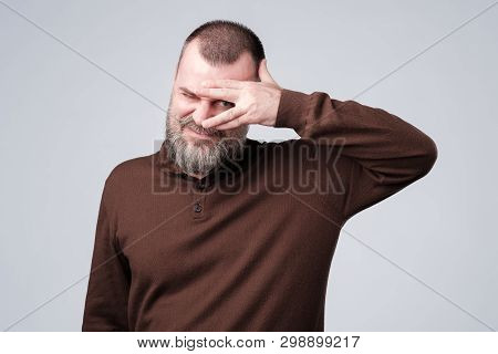 Man With Beard In Brown Pulover Peeping Through Fingers