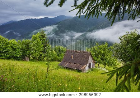 Summer Mountain Panorama. Small Wooden House Cottage And Barn On Green Mountain Valley On Bright Fog