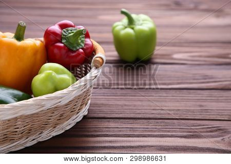 Fresh Pepper In A Basket On Brown Background. Red, Green, Yellow Paprika On Table.