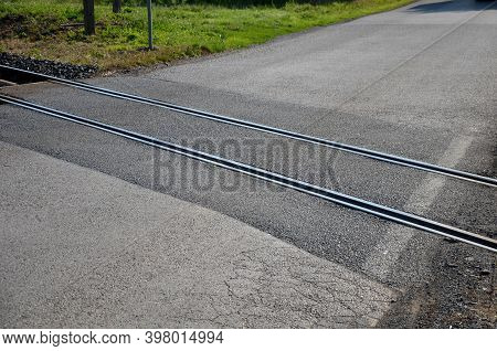 Train Tracks Leading Across The Asphalt Road Obliquely To The Direction Of Travel. There Is A Risk O