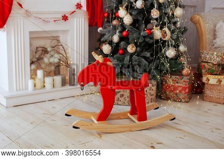 Christmas Interior Of Living Room With Wooden Elk Rocking Chair, Christmas Tree, Fireplace And Gifts