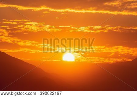 Sunset Sky With Orange Clouds. A Beautiful, Colorful, Abstract Mountain Landscape With Sun In A Oran