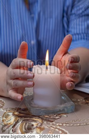 Magician, Sorcerer, Psychologist At Work. Women's Hands Embrace A Lit White Candle