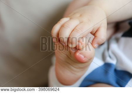 A Detail Picture Of Child´s Hands And Feet. The Child Is Holding Its Feet And Exploring Its Body And
