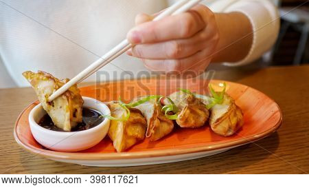 Young Woman Eating Japanese Gedza Dumplings In Cafe.