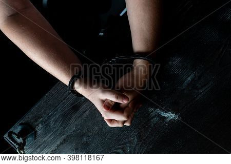 A Man With Hands In Handcuffs At Table, Concept. The Hands In Handcuffs Squeeze And Unclench Hands, 