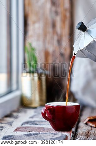 Espresso Coffee Is Poured From A Geyser Coffee Maker Into A Red Mug. Steam Rises Above The Cup. Clos