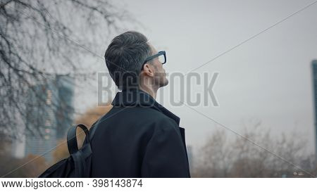 Man In Black Coat Walk On Background Of Business Skyscrapers, Slow Motion. Gimbal Profile Shot Of Bu