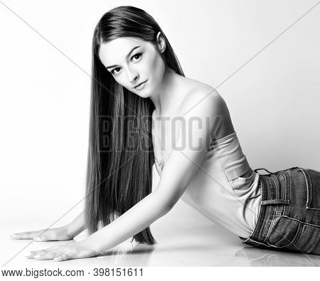 Portrait Of Young Smiling Pretty Woman Model With Silky Long Straight Hair Posing On Floor Over Whit