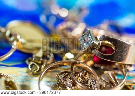 Real Gold Rings With Diamonds, Gems, Neckless Close Up Macro Shot On Colorful Surface.