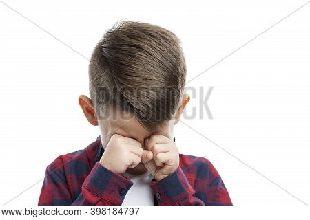 A 7-year-old Boy Cries And Rubs His Eyes With His Hands. Close-up. Isolated On White Background.