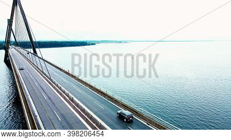 Large Highway Bridge Spanning Over A Bay, With Cars And Trucks Driving. Aerial View.