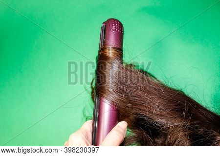 A Lock Of Dark Hair Is Wrapped Around A Hot Styler. Close Up.