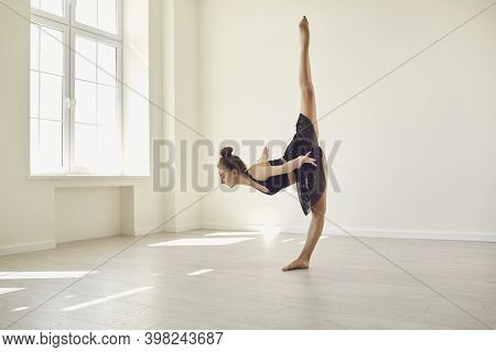 Young Female Gymnast Doing Vertical Standing Split Balance During Rehearsal In Modern Gym Or Studio