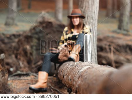 Woman In Yellow Shirt And Hat Siting On The Felled Tree In The Autumn Forest