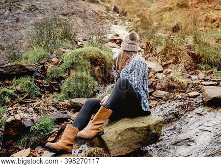 Happy Woman In Yellow Shirt And Hat Sitting On Stone In Strem  In The Autumn Forest