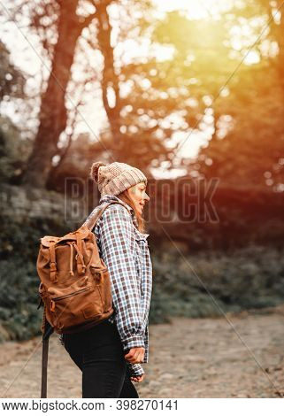 Woman In Yellow Shirt And Hat Walking Along The River In The Autumn Forest