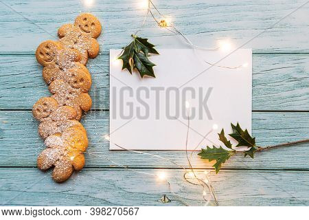 Gingerbread Cookies, Gingerman, Arranged On A Blue Table With Holly, Traditional Christmas Plant, Ch