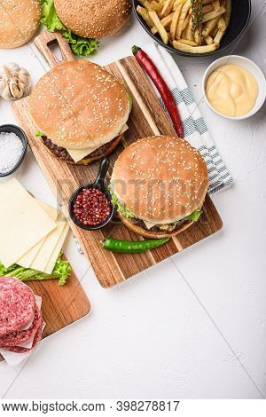 Set Of Hamburgers And Raw Ingredients On White Background, Top View With Copy Space