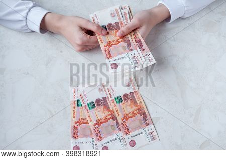 A Girl In A White Shirt At The Table Counts Money, A Bank Employee