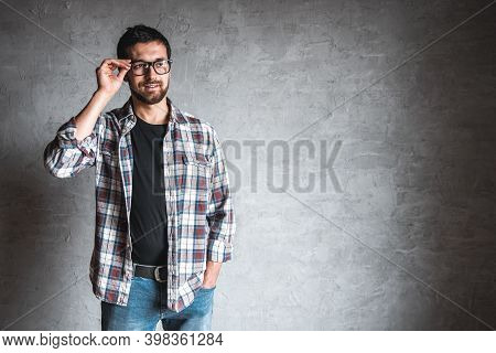 Men In A Plaid Shirt On A Background Of Gray Concrete Wall. Remote Work