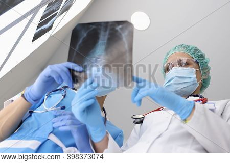 Two Doctors In Protective Mask Discuss X-ray Of Lungs With Atypical Pneumonia In Hospital In Covid E
