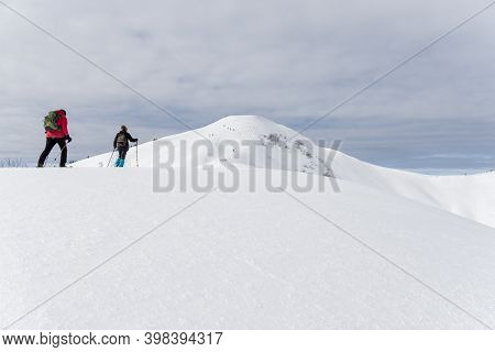 Senior Couple Is Snowshoe Hiking In Alpine Snow Winter Mountains. Allgau, Bavaria, Germany.