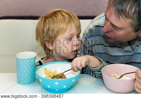 Grandfather And Grandson Have Breakfast At The Table, Close Uip