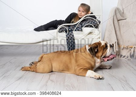 In The Girls Bedroom There Is An English Bulldog Next To Her Bed And The Child Is Lying On The Bed A