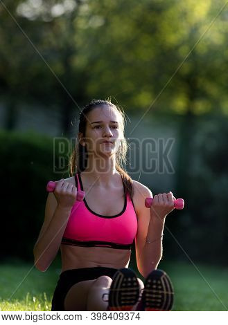 Fit Teenage Girl Doing Exercise With Dumbbells On Mat On Grass In Park Un Summer Time. Healthy Lifes