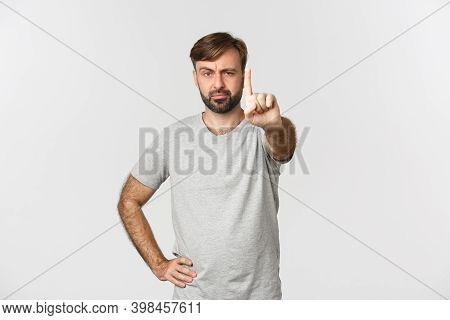 Portrait Of Serious Adult Man With Beard, Wearing Gray T-shrit, Shaking Finger With Disappointed Fac