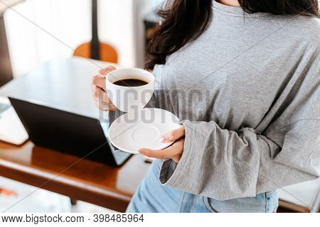 Woman Relxing Time While Working And Hold Cup Of Coffee At Working Place.