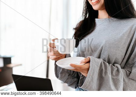 Woman Relxing Time While Working And Hold Cup Of Coffee At Working Place.
