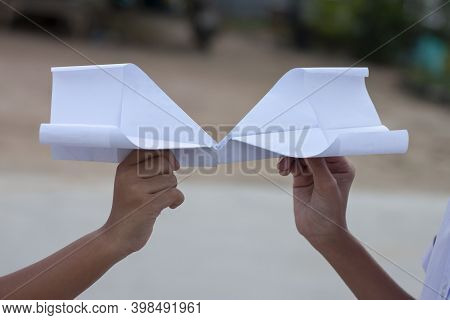Hand Of Children Holding Paper Airplane Fold From Reuse Paper. It Is A Toy Born Of Creativity And Im