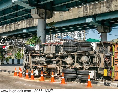 A View Of Under The Truck Carrying A Container Overturned On A Road Under A Bridge Over An Intersect